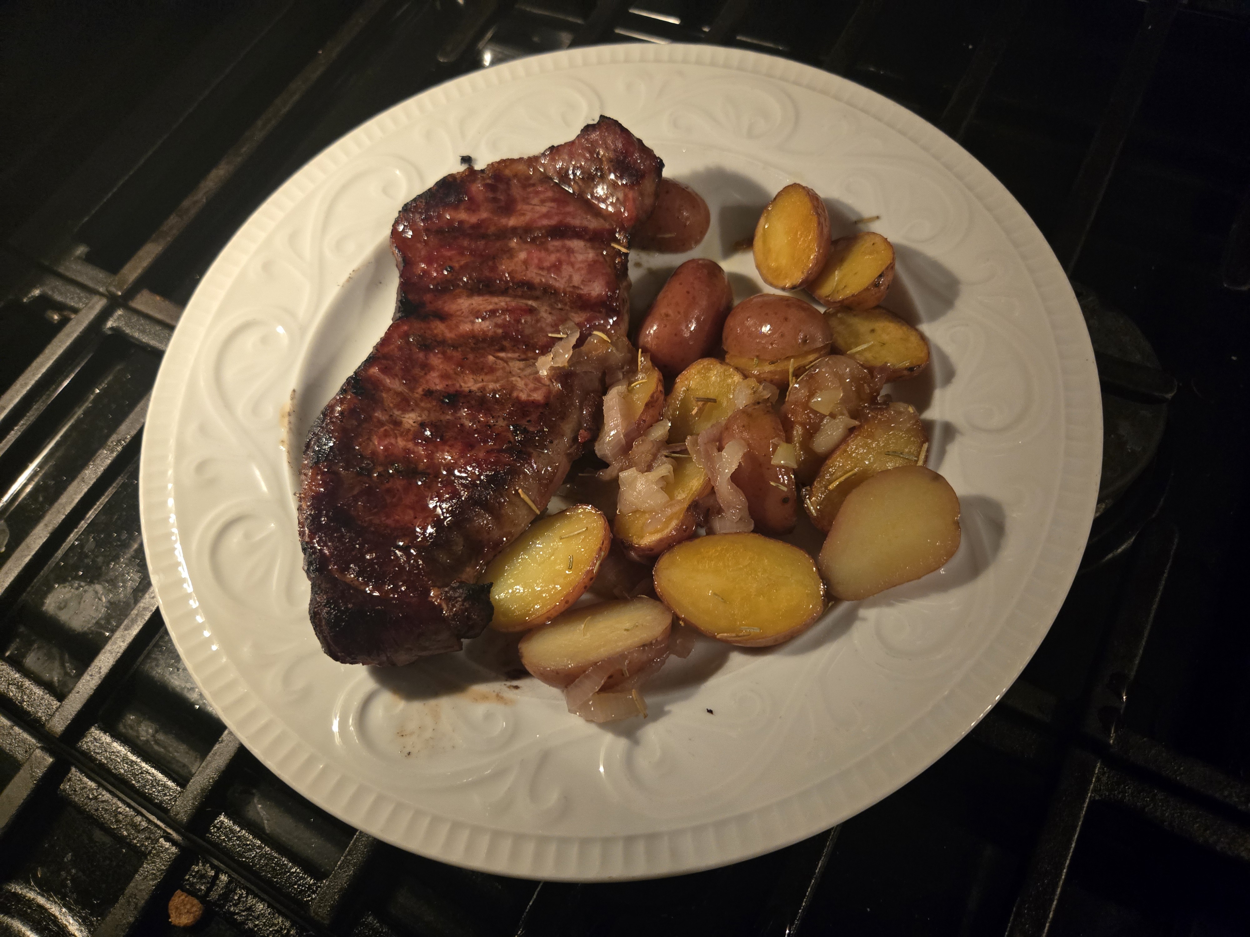 Grilled steak and potatoes with shallots on a plate.